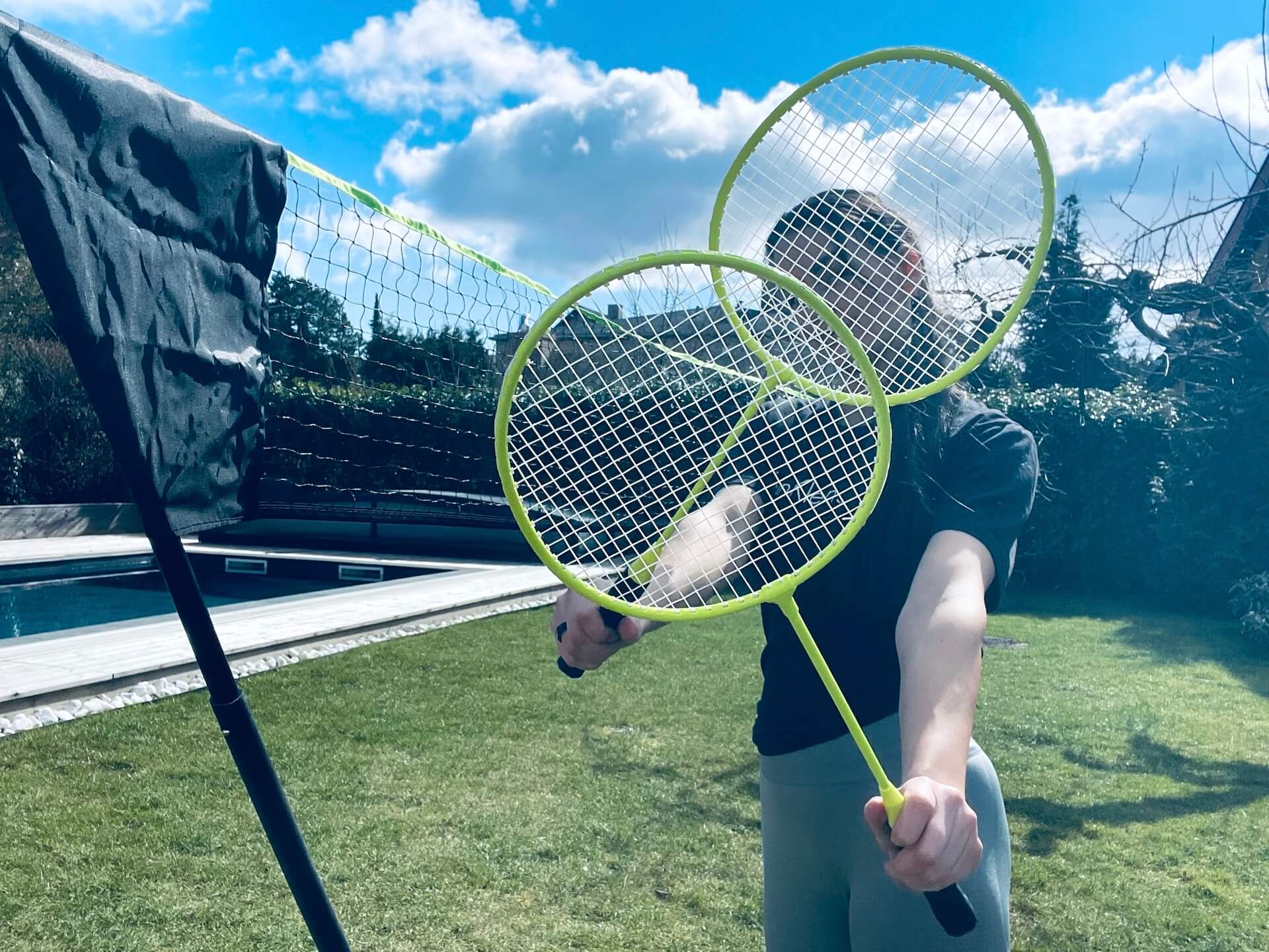 Kvinde der står med to ketchere til Badmintonnet til haven fra Hobbysport